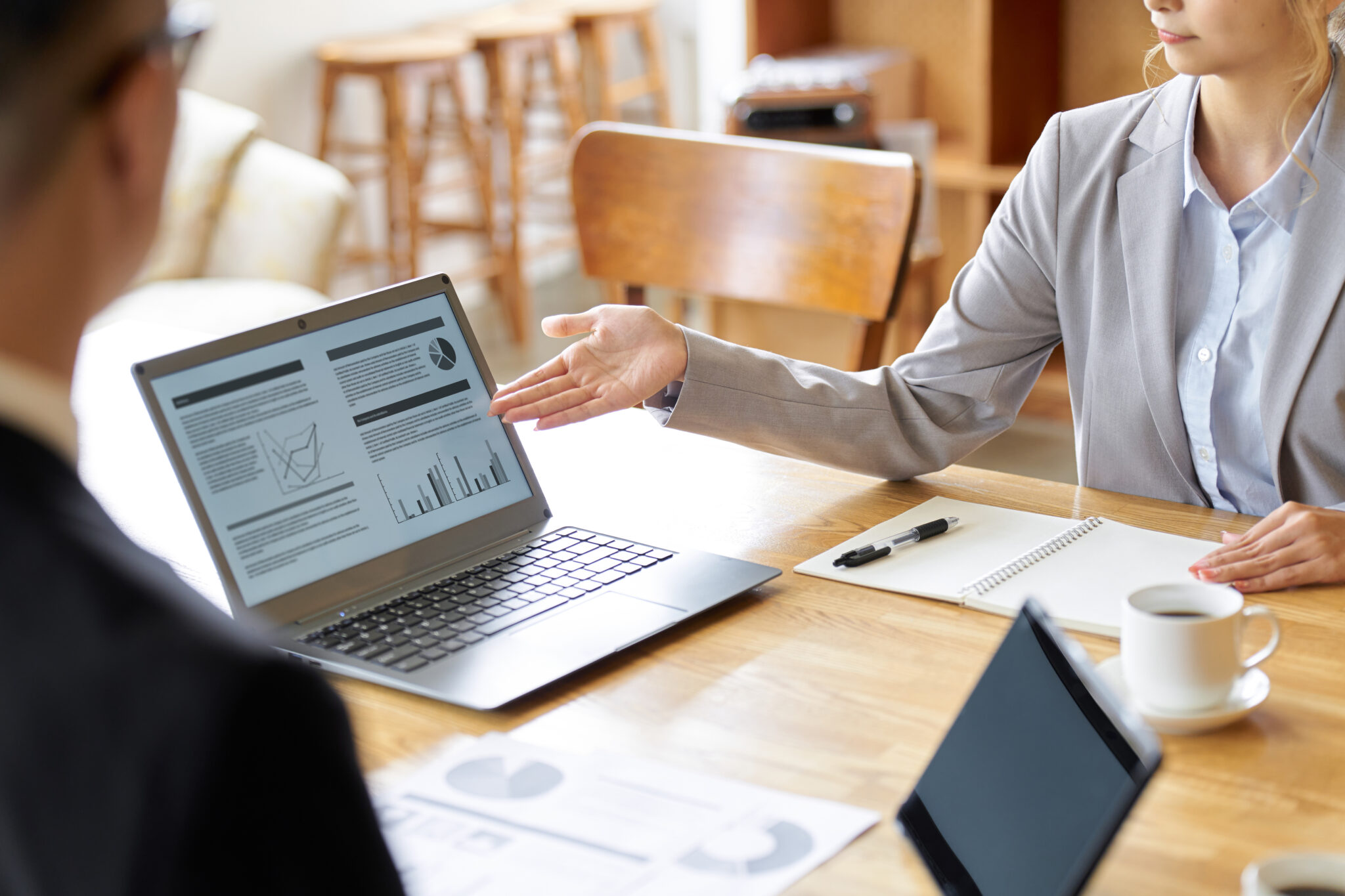 Zwei Geschäftspersonen in einem Meeting, die auf einem Laptop Verkaufsdaten und Diagramme besprechen. Die Szene symbolisiert die Hauptaufgabe eines Chief Revenue Officers (CRO) durch strategische Entscheidungen und Datenanalyse. Eine Person zeigt auf den Bildschirm, auf dem Grafiken und Berichte zu sehen sind.