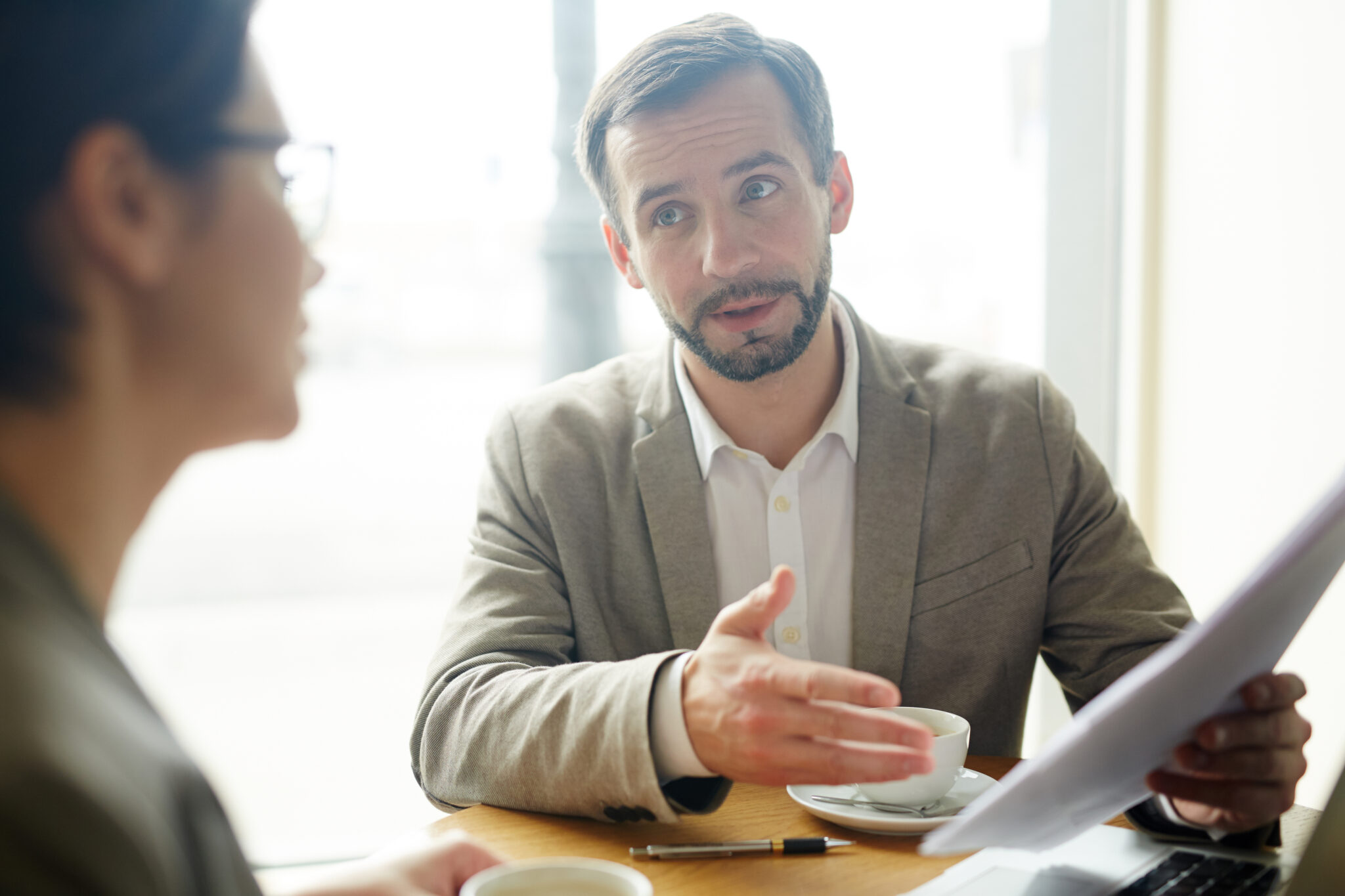 Ein Headhunter und eine Kandidatin in einem formellen Gespräch in einem Büro. Der Headhunter, der als Mann im Anzug dargestellt wird, erklärt etwas, während er ein Dokument in der Hand hält.