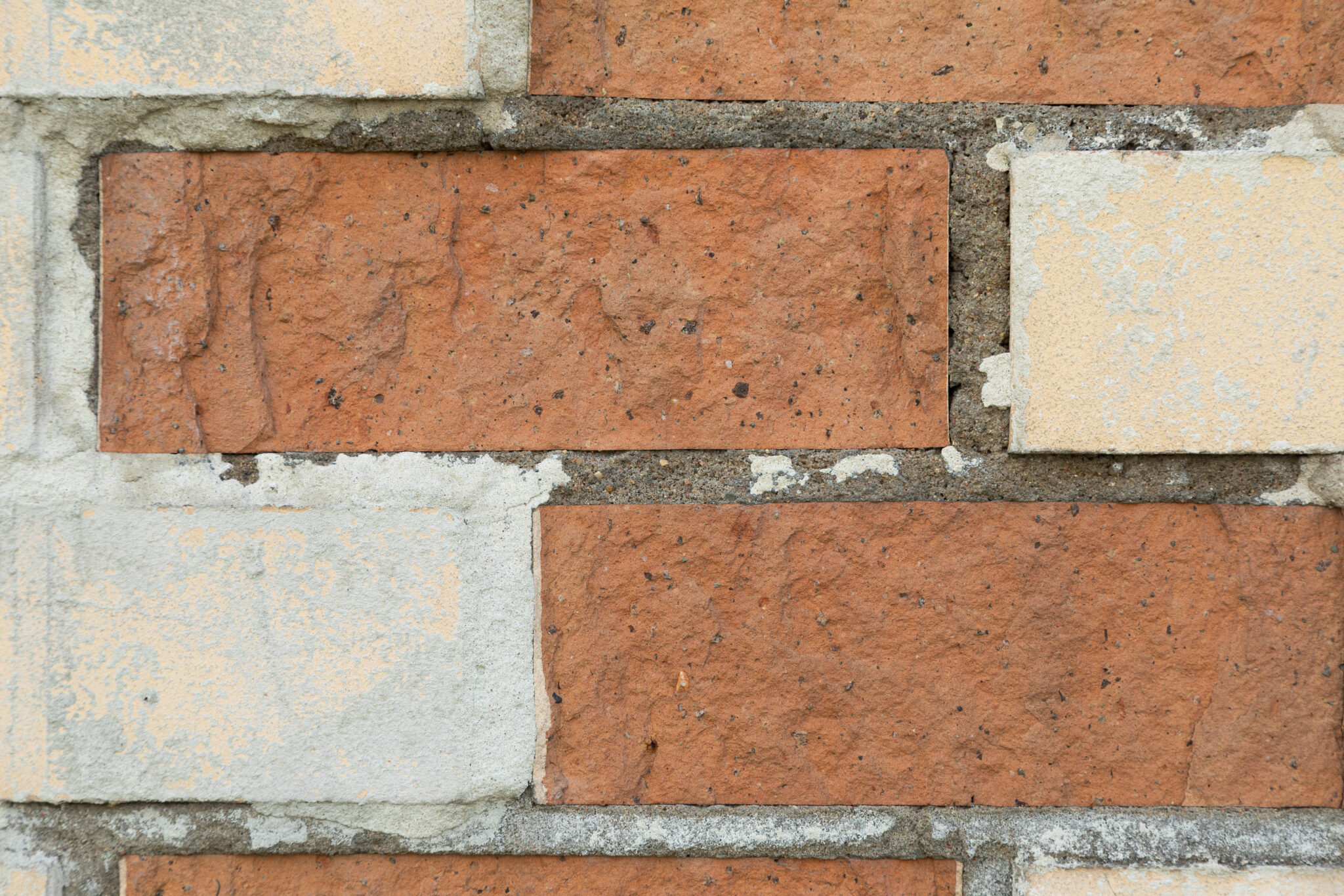 Nahaufnahme einer Mauer aus unterschiedlich großen Ziegelsteinen mit sichtbaren Lücken. Die roten und hellen Ziegel symbolisieren Stabilität, während die Lücken metaphorisch für den Fachkräftemangel stehen. Das Bild illustriert das Problem des bevorstehenden Fachkräftemangels durch den demografischen Wandel.