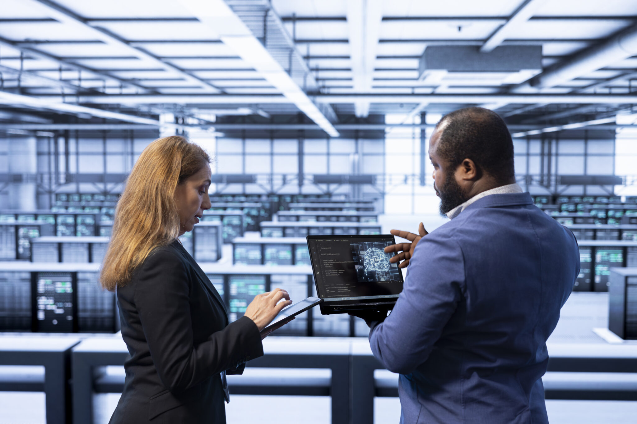 Fotografie eines CTOs in einem Rechenzentrum, der gemeinsam mit einer Kollegin mithilfe eines Laptops die Technologiestrategie im Einklang mit den Unternehmenszielen bespricht.