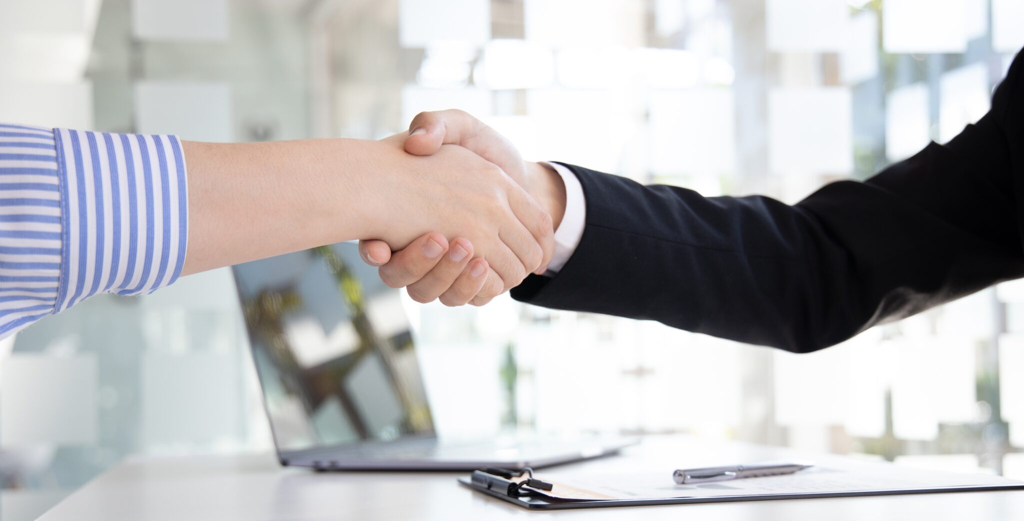 Personalberater und Kunde geben sich die Hand in einem modernen Büro, symbolisierend für professionelle und positive Interaktionen im Executive Search in Frankfurt.