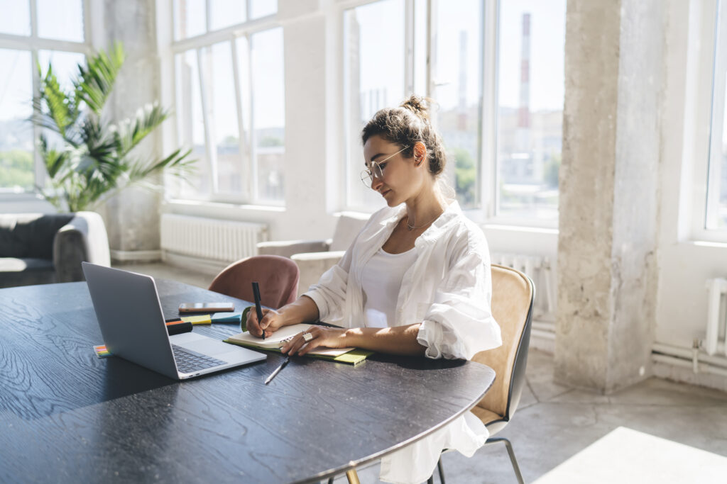 Junge Frau arbeitet fokussiert im Homeoffice.