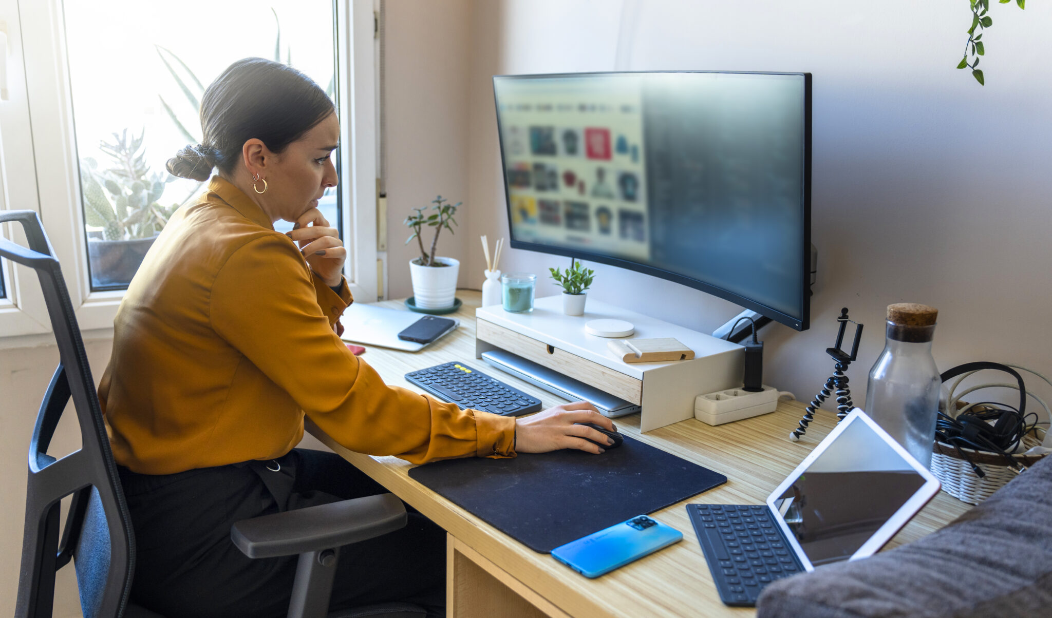 Frau arbeitet konzentriert an einem Schreibtisch im Homeoffice mit mehreren Bildschirmen und moderner Ausstattung. Darstellung der Produktivität im Homeoffice ohne Einbußen.