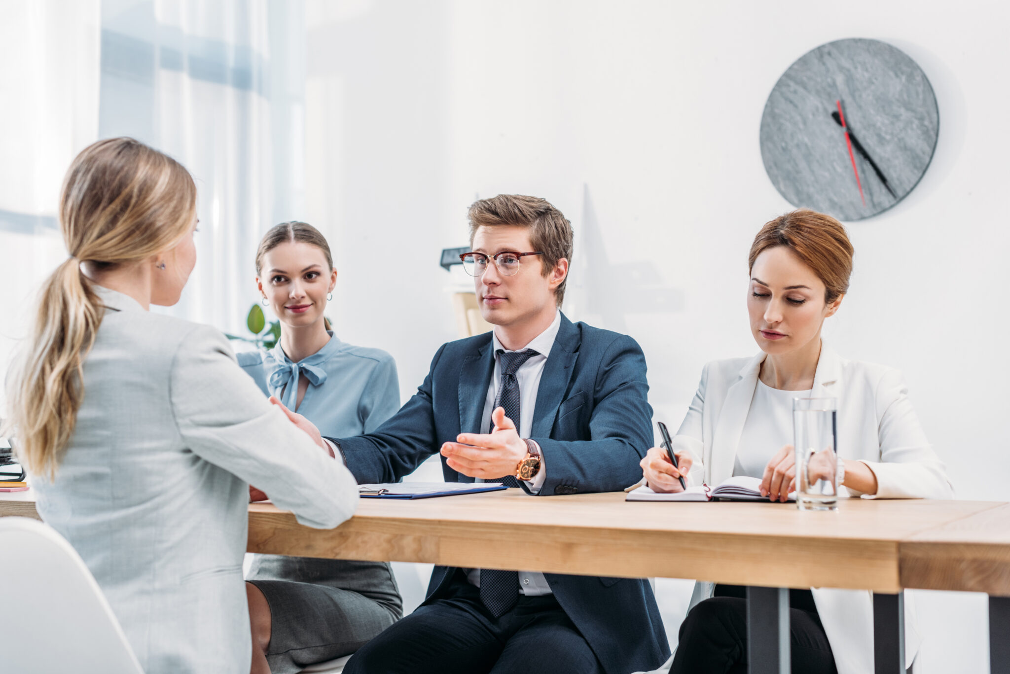 Bewerbungsgespräch: Drei Logistik-Recruiter in Businesskleidung sprechen mit einer Kandidatin am Tisch.