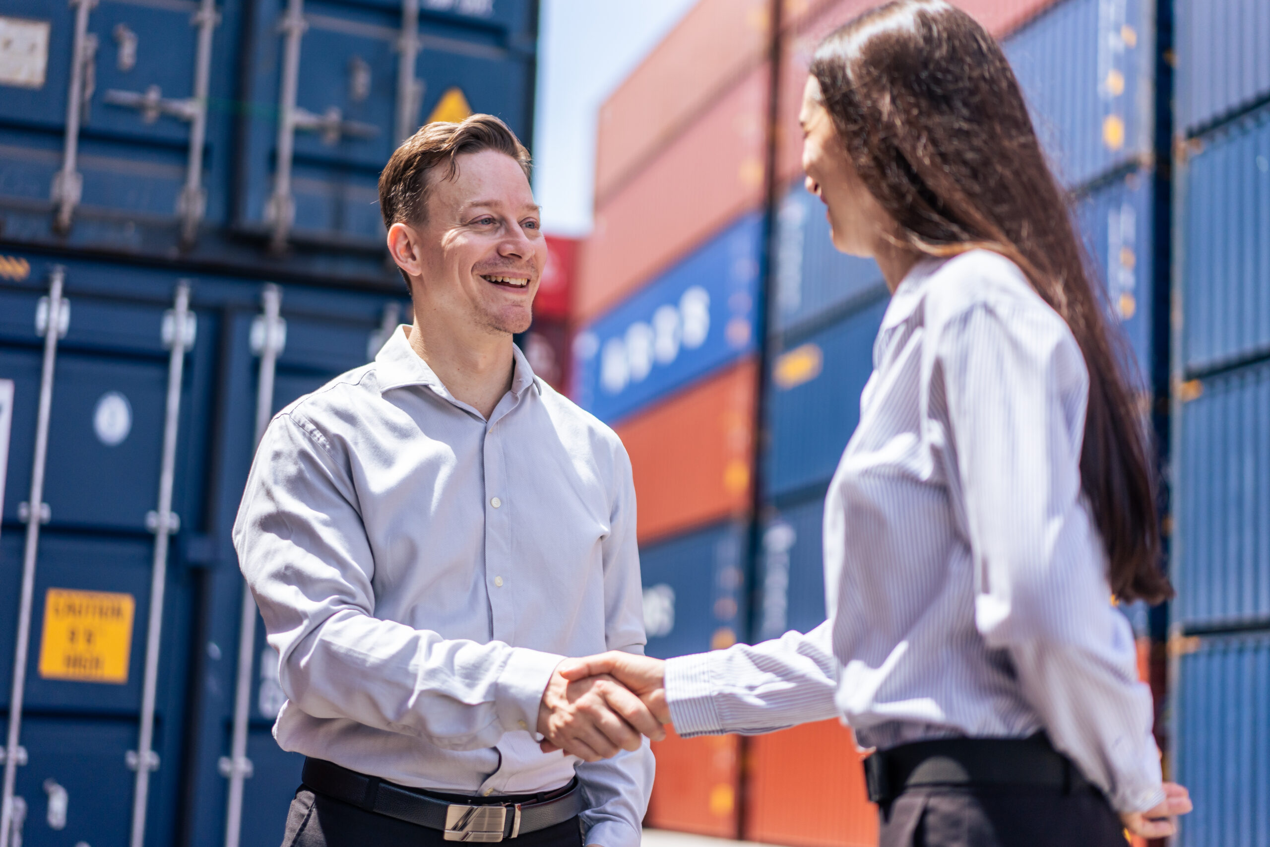 Junger Recruiter begrüßt Kandidatin in einem Container-Hafen.