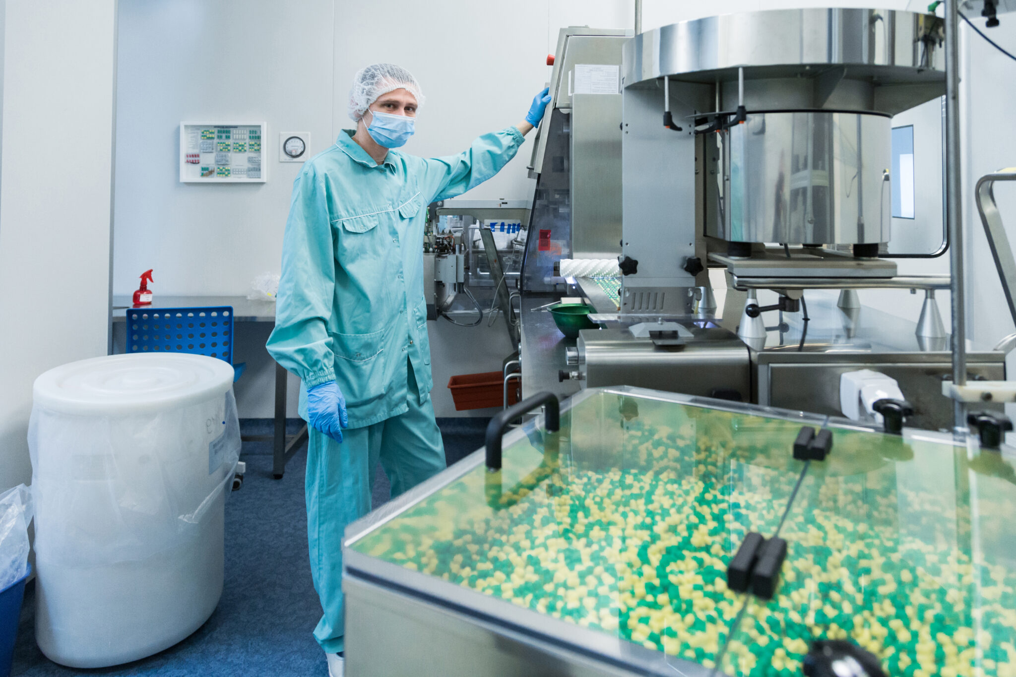 Mitarbeiter in steriler Pharmaproduktion bedient Maschine.