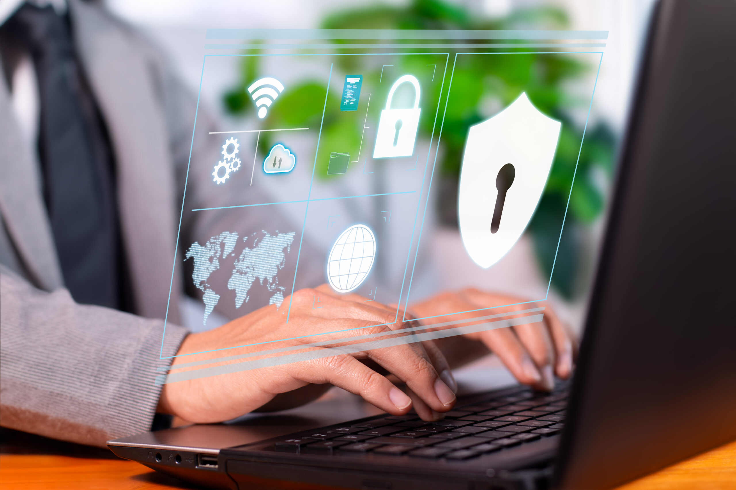 IT-Security-Spezialist tippt auf Laptop mit digitaler Schnittstelle für Cyber-Sicherheit, Icons für Schutz und Netzwerke.