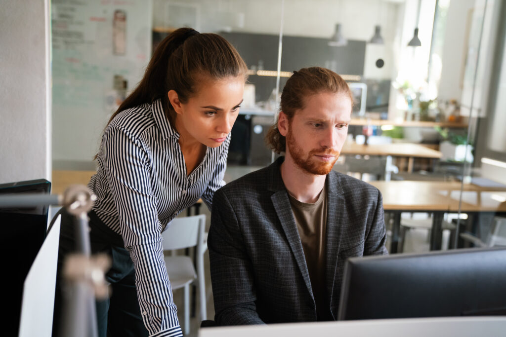 Zwei Personen arbeiten zusammen an einem Computer in einem modernen Büro.