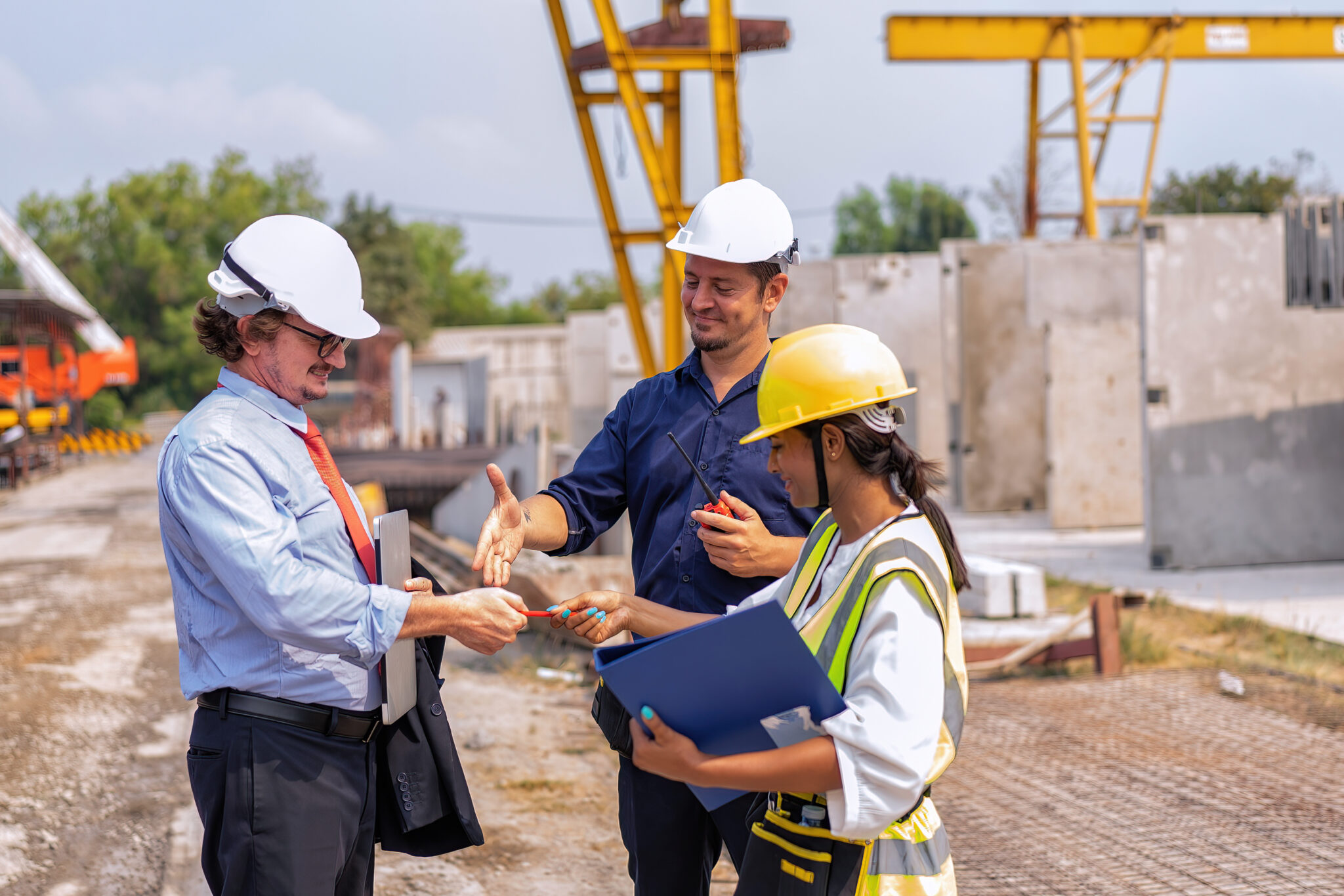 Drei Bauleiter in Schutzhelmen und Arbeitskleidung besprechen sich auf einer Baustelle.