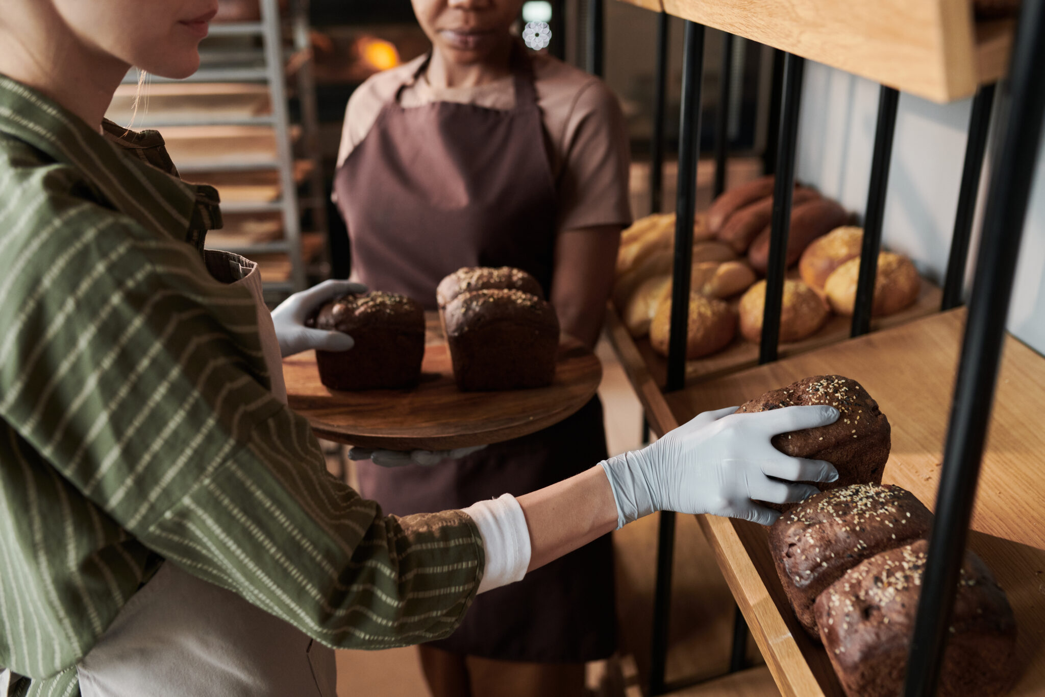 Zwei Personen in einer Bäckerei räumen gemeinsam frisches Brot in ein Regal.