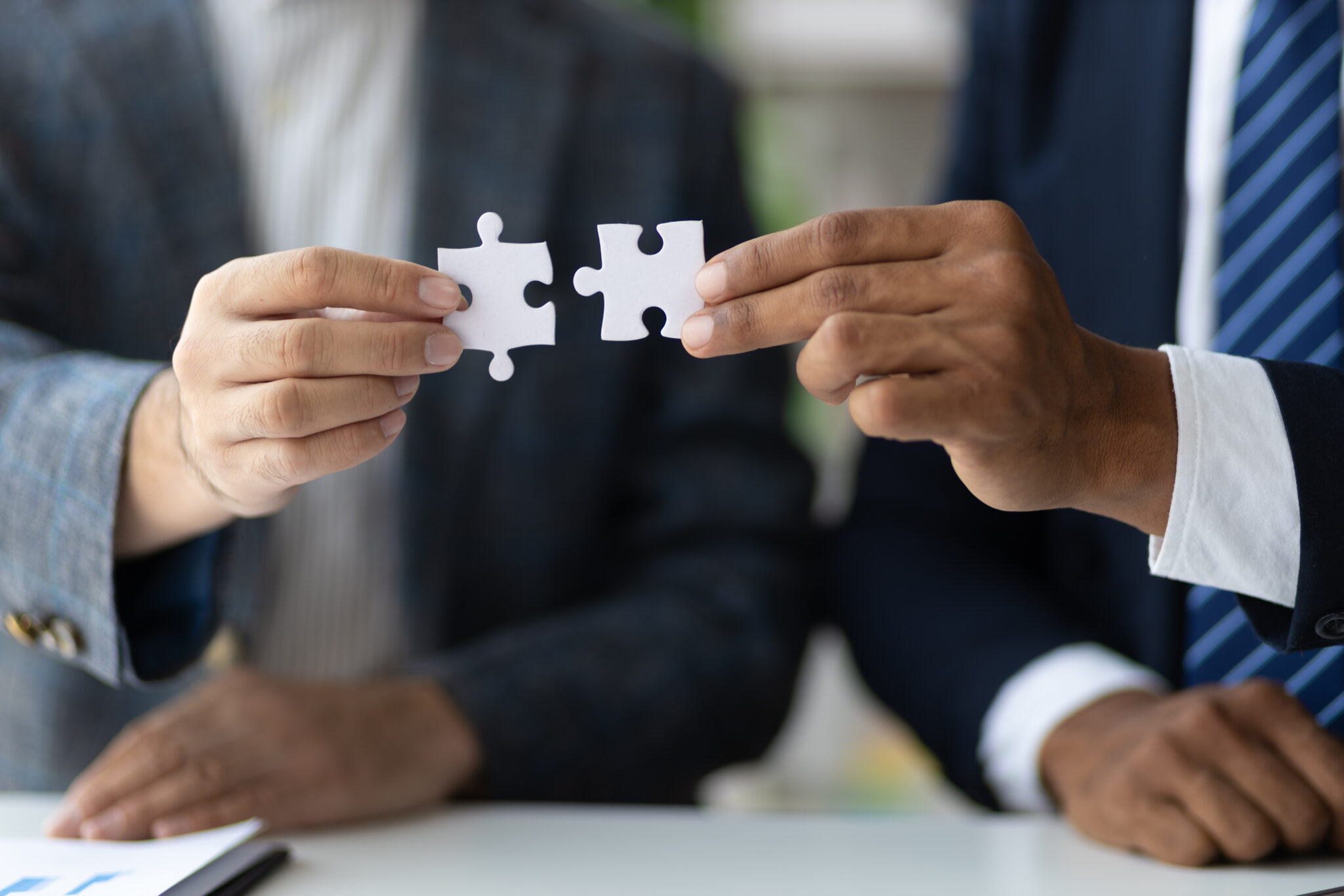 Zwei Männer halten je ein Puzzleteil in den Händen und fügen sie zusammen.